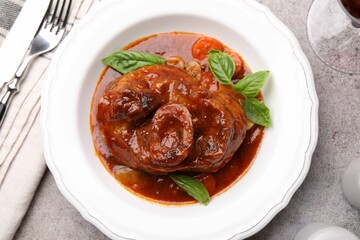 Traditional ossobuco dish with beef steak served on grey table, flat lay