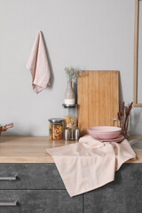 Wooden kitchen counter with cutting board, utensils and plates