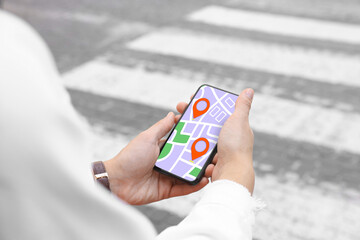Woman looking at city map on her mobile phone outdoors, closeup
