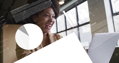 Analyzing woman wearing blazer reviewing overlays at office desk with laptop, pie chart, copy space