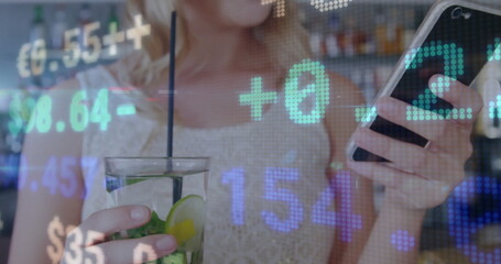 Holding smartphone and sipping mint lime cocktail at bar counter, showing floating numeric overlays