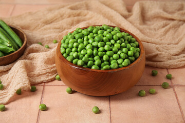 Bowl with fresh green peas on pink tile table