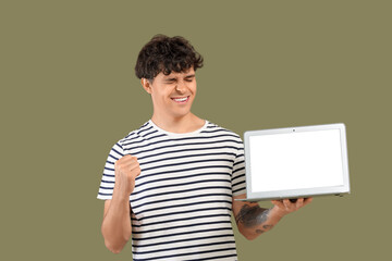 Happy male programmer with blank laptop on green background