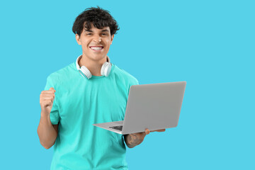 Happy male programmer with laptop on blue background