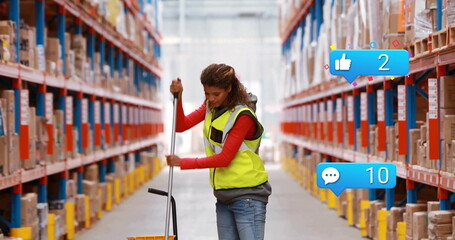 Warehouse worker wearing safety vest pushing pallet jack in warehouse aisle, with shelving racks