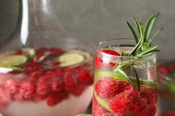 Glass and glass of fresh raspberry lemonade with rosemary on grey background, closeup