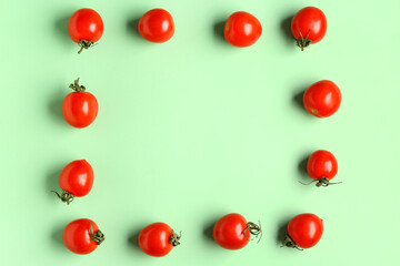 Frame made of fresh cherry tomatoes on green background