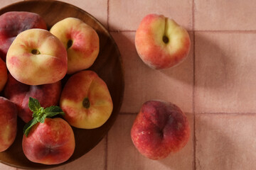 Wooden plate with sweet fig peaches and mint on pink tile background