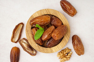 Bowl with dried dates on light background