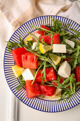 Plate of tasty watermelon salad on white wooden background