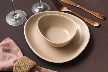 Elegant table setting with rose gold cutlery on brown background, closeup