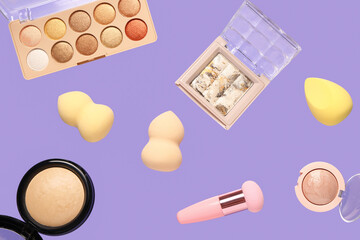 Flying decorative cosmetics on lilac background
