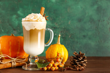 Glass cup of tasty pumpkin latte with cinnamon and star anise on wooden table