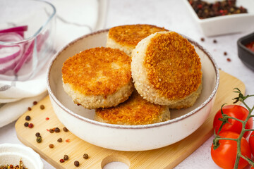 Bowl of tasty meat cutlets on white background
