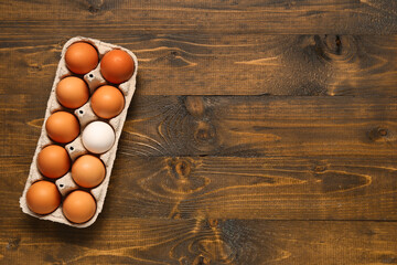 Eggs in carton box on wooden background