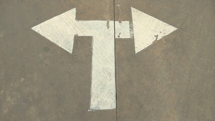 White left and right turn arrow symbols on concrete road surface.,arrow sign on a concrete wall
