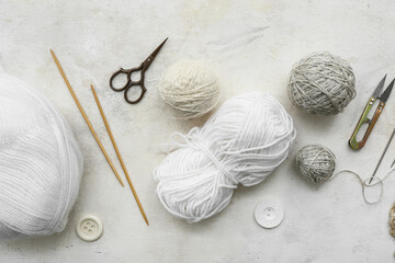 Knitting needles, yarn balls and scissors on white background