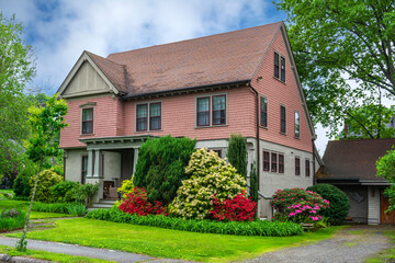 Traditional clapboard and stucco family home surrounded by vibrant spring flowers in Newton,...
