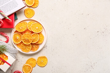 Plate with dried orange slices and Christmas candy canes on white background