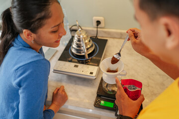 A couple enjoys brewing coffee together with a scale and pourover method, creating warmth