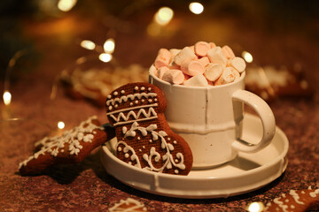 Cup of hot cocoa with gingerbread cookies on grunge table against blurred Christmas background