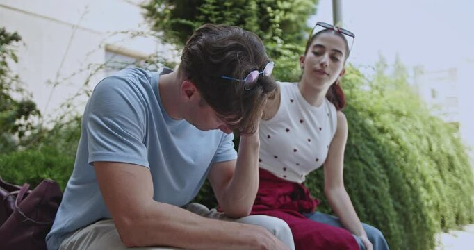 A concerned female friend offers solace and understanding to an upset male student. He appears overwhelmed by academic stress and difficulties during his university studies.