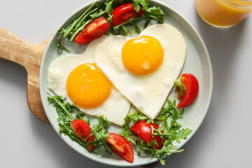Plate with tasty fried eggs, tomatoes, arugula and glass of juice on white background, closeup