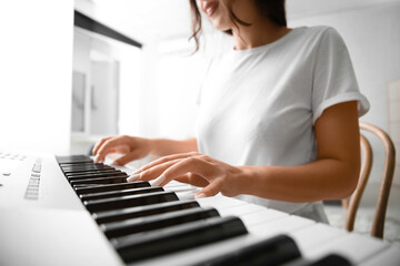 Young woman playing synthesizer at home