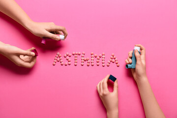 Child's hands with inhalers and word ASTHMA made of pills on pink background