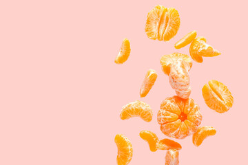 Flying sweet peeled mandarins on pink background