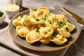 Plate of boiled dumplings with cheese and basil on grey background