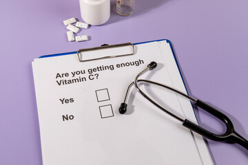 A white paper asks a critical health question about vitamin C intake, placed beside a stethoscope...