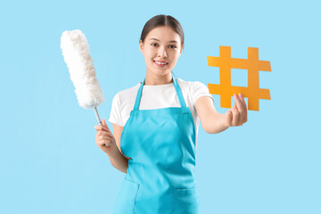 Female janitor with dust brush and hashtag sign on color background