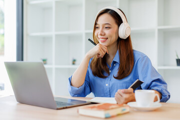 Beautiful young Asian woman college student wearing white headphones at classroom. College student working on the college campus. back to school concept
