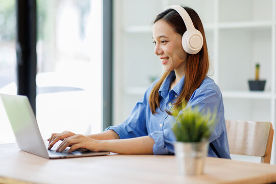 Beautiful young Asian woman college student wearing white headphones at classroom. College student working on the college campus. back to school concept
