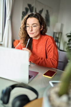 Young girl female student using laptop elearning or remote working at home office looking at computer watching webinar, learning training, studying online or video calling for work meeting. Vertical