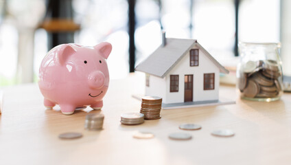 house model and money coins saving for concept saving money for buying a house, investment mortgage...