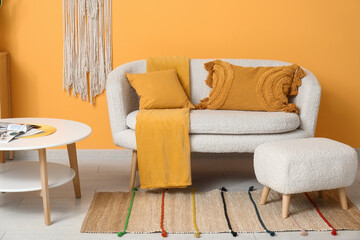 Stylish interior of living room with white armchair, cozy sofa and coffee table