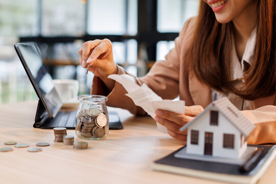 Hand plans home refinance. Pressing calculators, House model, buy or rent, calculators on desk. Saving for property purchase, optimal mortgage payment. Tax, credit analysis for financial planning.
