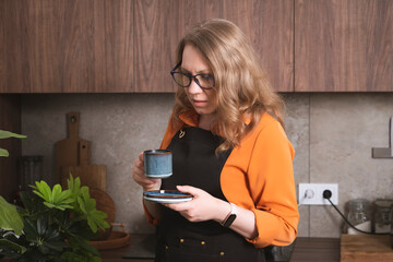 Woman enjoys espresso in a modern kitchen while savoring a coffee break