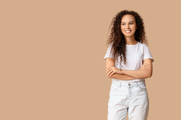Happy young African-American woman on beige background