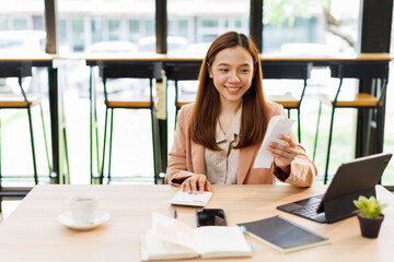 asian young woman hand checking list with bill for calculate accounting expense credit card payment...