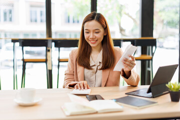 asian young woman hand checking list with bill for calculate accounting expense credit card payment...