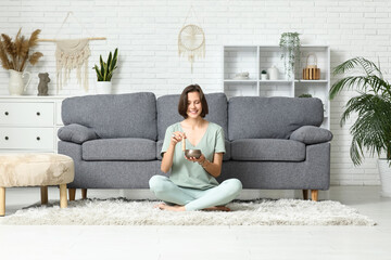 Young woman with Tibetan singing bowl meditating while sitting on floor at home