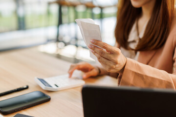 asian young woman hand checking list with bill for calculate accounting expense credit card payment on due deadline, trying to find money to pay debt on table. Business financial concept,
