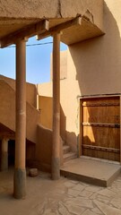 A photo of the old mud houses in Najd, Saudi Arabia, featuring wooden doors, earthen walls, narrow...