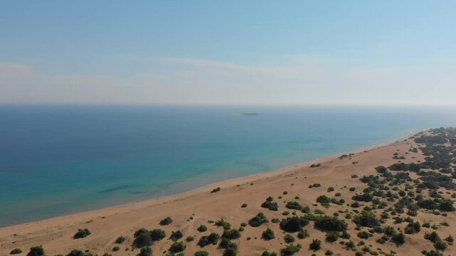 An breathtaking aerial drone view showcasing the golden sands of Issos Beach meeting the turquoise waters of the Ionian Sea, with the protected wetland of Lake Korission nestled behind the dunes on Co