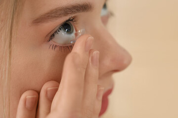 Young woman putting in contact lenses at home, closeup