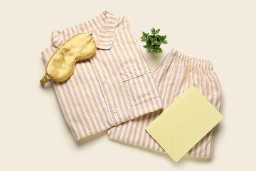 Female pajamas, sleeping mask and notebook on color background
