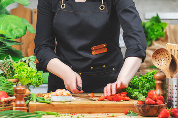 chef skillfully chops vegetables on a wooden cutting board in a lively kitchen adorned with fresh...